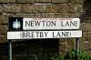 Newton Lane changes to Bretby Lane half way along its length, hence the two names on the street sign